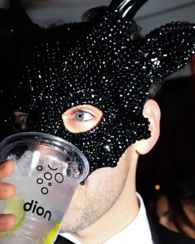 A masked guest with a Dion cup at a Dion party