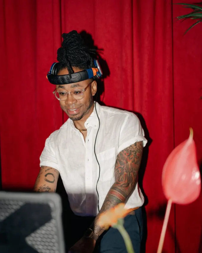 A DJ playing in front of a red curtain